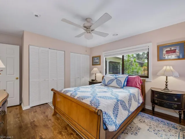 Bedroom 2 with multiple closets, dark wood-style flooring, and ceiling fan