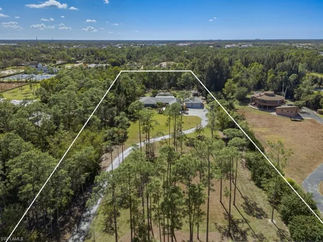 Aerial view of property and surrounding area featuring a heavily wooded area and property parcel outlined