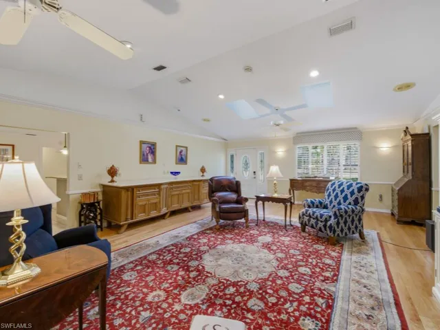 Living room featuring lofted ceiling, a ceiling fan, light wood-style floors, and ornamental molding