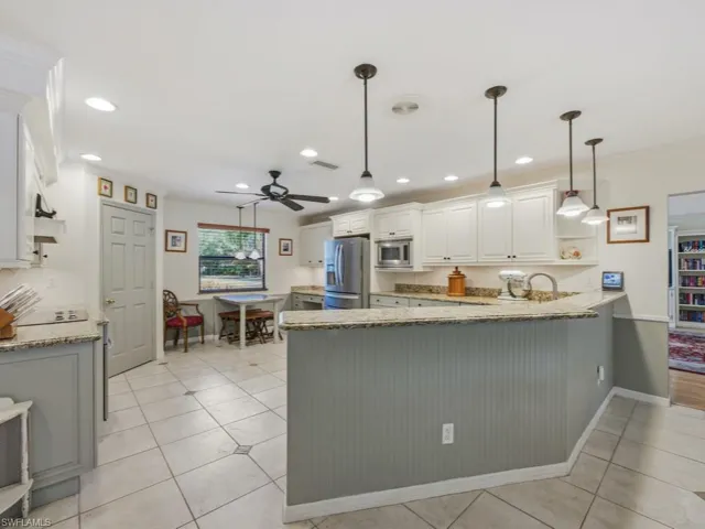 Kitchen with hanging light fixtures, light stone countertops, a peninsula, and ornamental molding