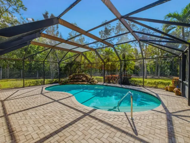 Swimming pool featuring a sunroom, a patio area, and glass enclosure