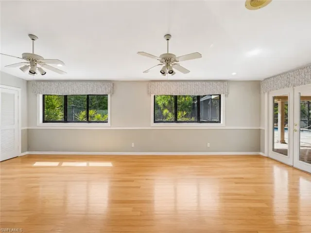 Spacious interior featuring wood-finish flooring, multiple ceiling fans, and a light color palette