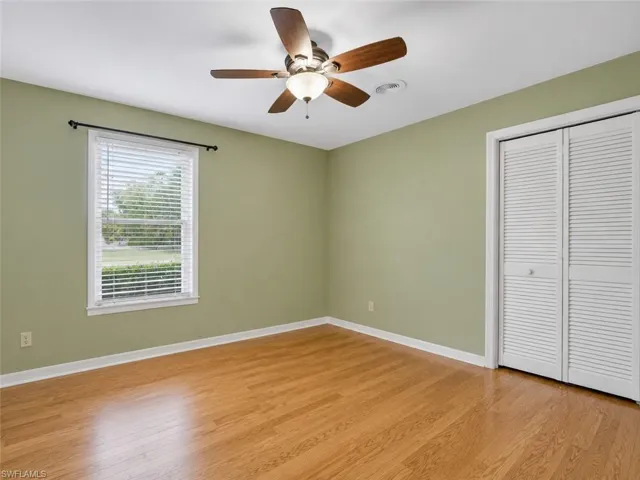 Room featuring wood-finish flooring, a window with horizontal blinds, and a ceiling fan with a light fixture