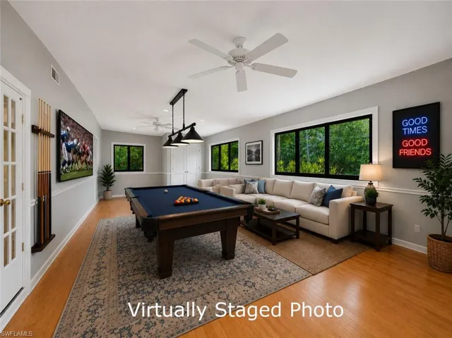 Spacious entertainment room featuring wood-finish flooring, recessed lighting, and multiple windows