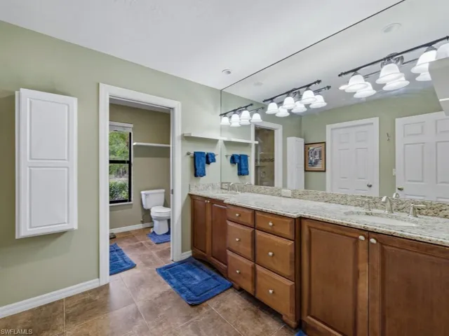 Full bathroom featuring double vanity, dark tile patterned flooring, and a shower
