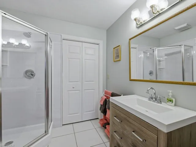 Full bath with a stall shower, a closet, vanity, and light tile patterned flooring