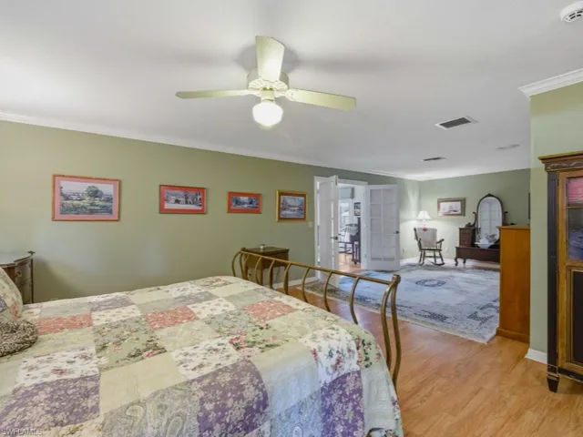 Bedroom featuring french doors, crown molding, light wood finished floors, and ceiling fan