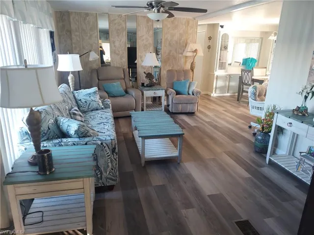Living room featuring ceiling fan, a healthy amount of sunlight, and dark hardwood / wood-style floors