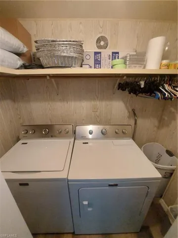 Clothes washing area featuring washer and dryer and wooden walls