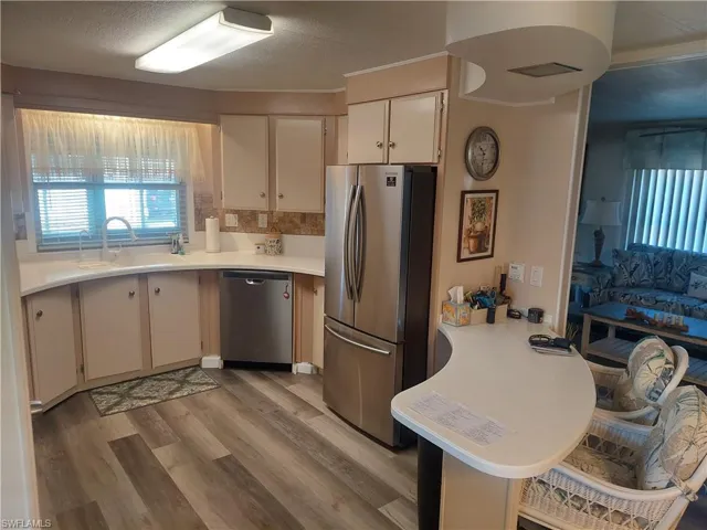 Kitchen featuring sink, a textured ceiling, stainless steel appliances, light hardwood / wood-style floors, and white cabinets