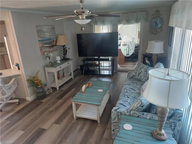 Living room with crown molding, ceiling fan, and wood finished floors