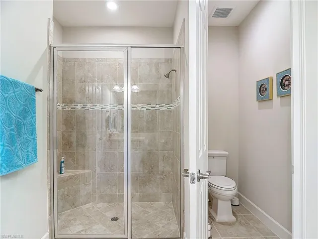 Bathroom featuring a beautifully tiled shower, tile flooring, and private toilet area