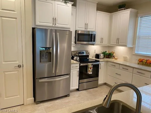 Kitchen with white cabinets, under cabinet lighting, light tile floors, pantry