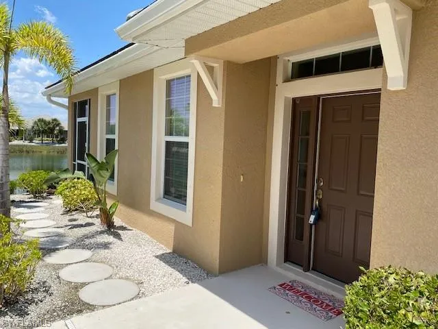 View of entrance to home with walkway to lake