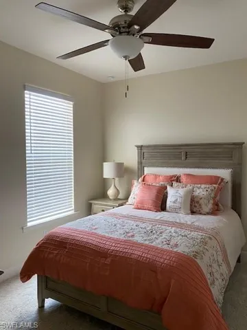 Carpeted guest bedroom with ceiling fan, and walk-in closet