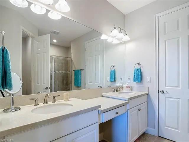 Bathroom featuring tile floors,  double sink vanity with extensive cabinet space and large walk-in closet