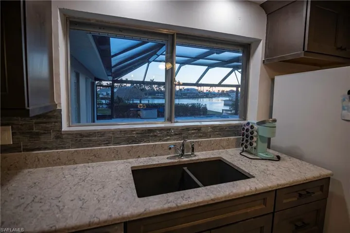 Kitchen featuring a dual basin sink with a chrome faucet, light-toned countertop, and dark wood cabinetry