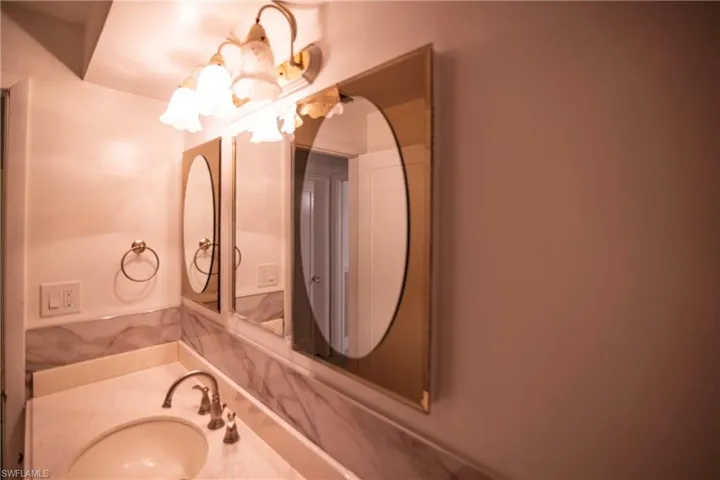 Bathroom vanity featuring a polished chrome faucet, an undermount sink, and a stone countertop with a matching backsplash