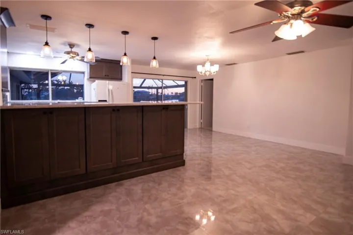 Kitchen island with dark wood-finish cabinetry and light-toned countertop, complemented by four pendant lights