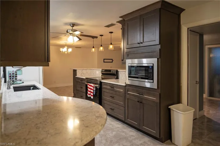 Kitchen featuring wood-finish cabinetry, light-toned countertops, and a built-in stainless steel microwave