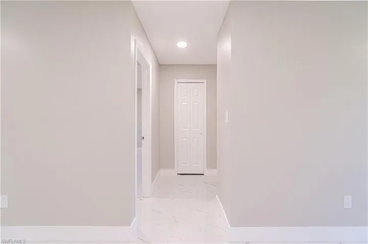Hallway with light marble finish flooring and recessed lighting
