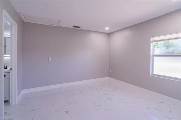 Spare room with light marble finish floors, attic access, and recessed lighting