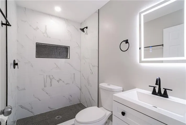 Bathroom with vanity and a marble finish shower