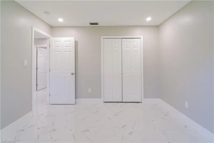 Unfurnished bedroom with light marble finish floors, a closet, and recessed lighting