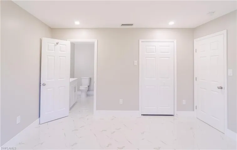 Unfurnished bedroom with light marble finish floors, recessed lighting, a closet, and ensuite bathroom