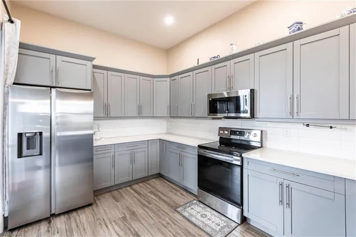 Kitchen featuring appliances with stainless steel finishes, gray cabinetry, decorative backsplash, light countertops, and light wood-style flooring