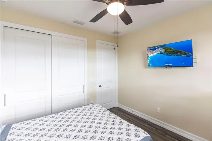 Bedroom featuring baseboards, dark wood-type flooring, a closet, and ceiling fan