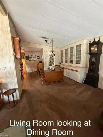 Dining space featuring wood walls, dark carpet, and hanging lights