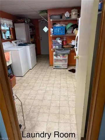 Laundry area with light floors, washing machine and dryer, and a paneled ceiling