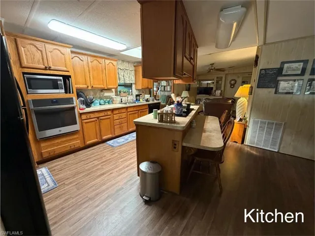 Kitchen featuring light countertops, stainless steel appliances, open floor plan, a kitchen breakfast bar, and light wood finished floors