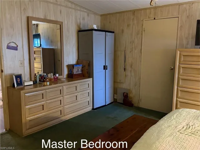 Bedroom with lofted ceiling, dark carpet, and wooden walls