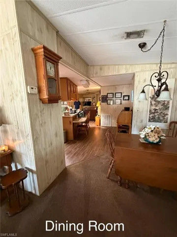 Dining area featuring wood walls, dark carpet, and a textured ceiling