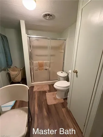 Bathroom featuring a stall shower, dark wood-style floors, and a textured ceiling