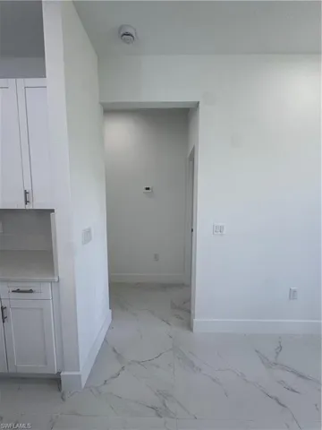 Hallway featuring light marble finish floors