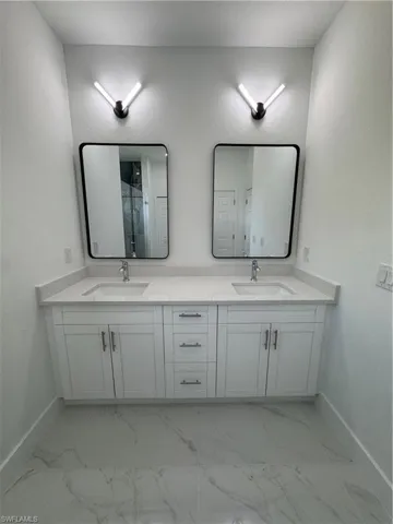 Full bathroom featuring a textured wall, double vanity, and a marble finish shower