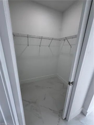 Walk in closet with light marble finish floors