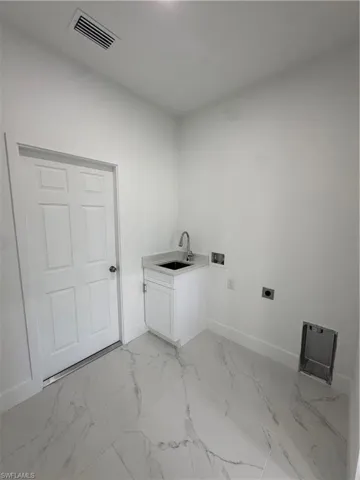 Laundry area with hookup for a washing machine, light marble finish floors, electric dryer hookup, and cabinet space