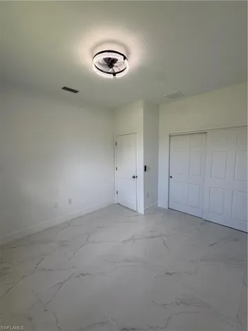 Unfurnished bedroom featuring light marble finish flooring and a closet