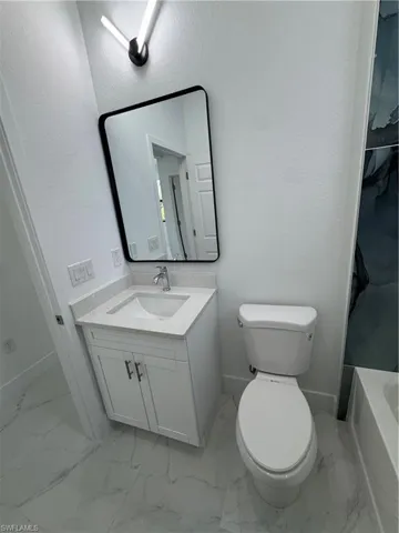 Full bathroom with vanity, a textured wall, a bath, light marble finish flooring, and a shower with curtain