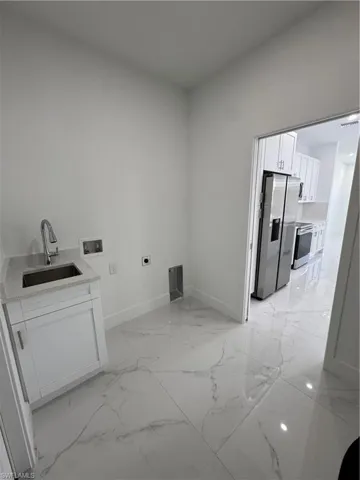 Laundry room featuring washer hookup, hookup for an electric dryer, light marble finish flooring, and cabinet space