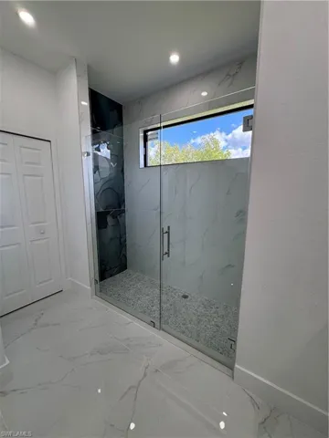Full bathroom featuring a marble finish shower, light marble finish flooring, and recessed lighting