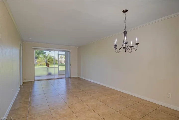 Unfurnished room featuring crown molding, light tile patterned floors, and a chandelier