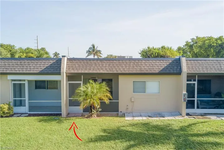 Rear view of property featuring a shingled roof, mansard roof, and stucco siding