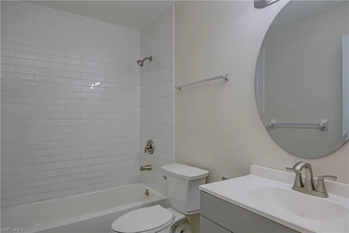 Bathroom featuring vanity, bathtub / shower combination, and a textured wall