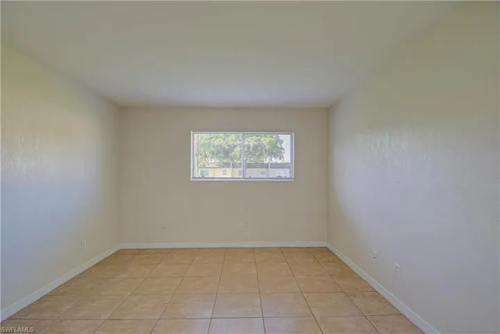 Empty room with light tile patterned flooring and baseboards