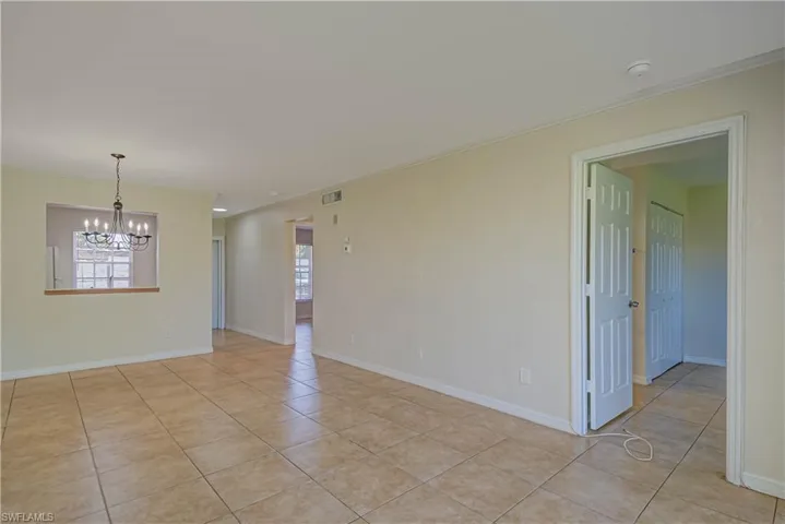 Unfurnished room with healthy amount of natural light, light tile patterned floors, crown molding, and a chandelier